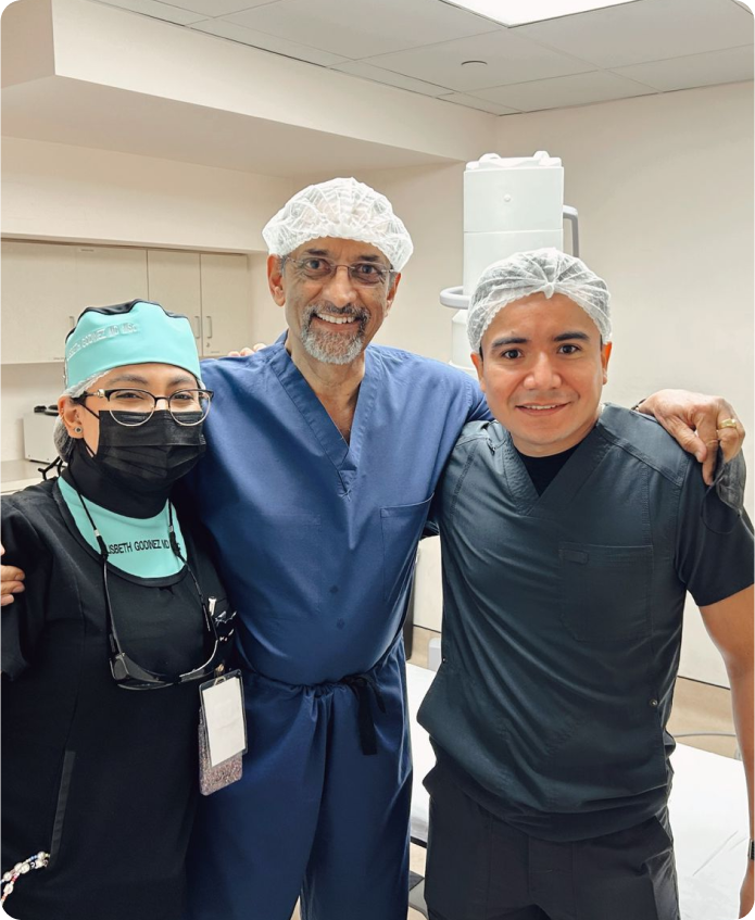 Equipo de tres medicos posando abrazados para foto, mujer a la izquierda, hombre al centro, hombre a la derecha